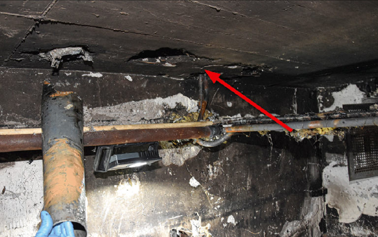 Bild 2 / In der Decke des Brandraumes im Keller befinden sich die Öffnung für die Ascheentsorgung und daneben eine Lüftungsöffnung (Pfeil).