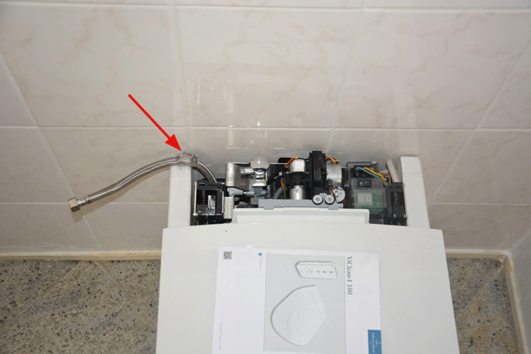 Bild 1 / Im hinteren Bereich des Dusch-WCs befindet sich die Steuerungstechnik. Der beschädigte Schlauch hängt heraus (Pfeil).