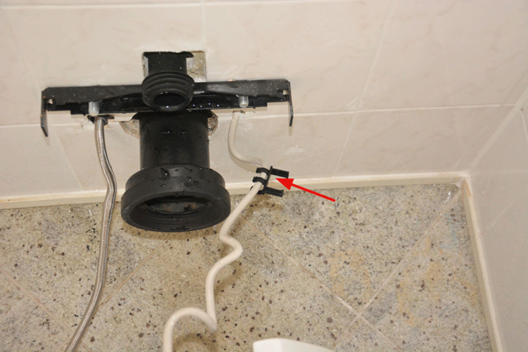  Bild 3 / Nach Demontage des WCs: Am Kabel ist die Kunststoffführung vorhanden (Pfeil), am Schlauch fehlt diese.