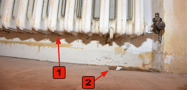 Bild 2 / Im Wohnzimmer ist der Heizkörper an der Unterseite gerissen (1). Das Parkett zeigt Feuchteschäden (2).